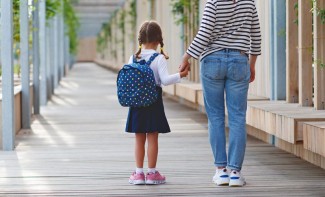 Photo: Little girl sitting outside school with her backpack and snacks