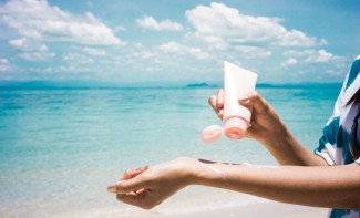 Photo: Woman applying suncreen on the beach