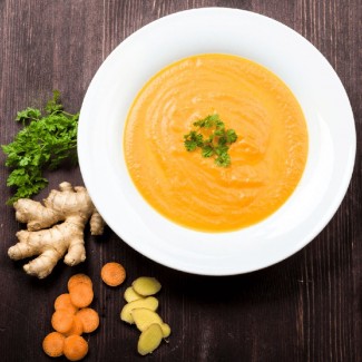 Photo: Carrot Ginger Soup next to slices of ginger, carrot and parsley